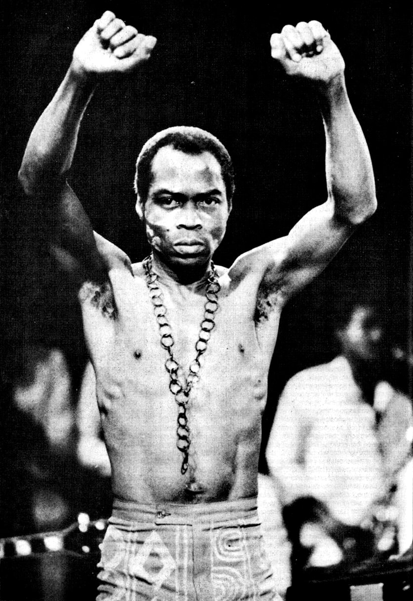 Fela Kuti on stage, shirtless, with both fists raised